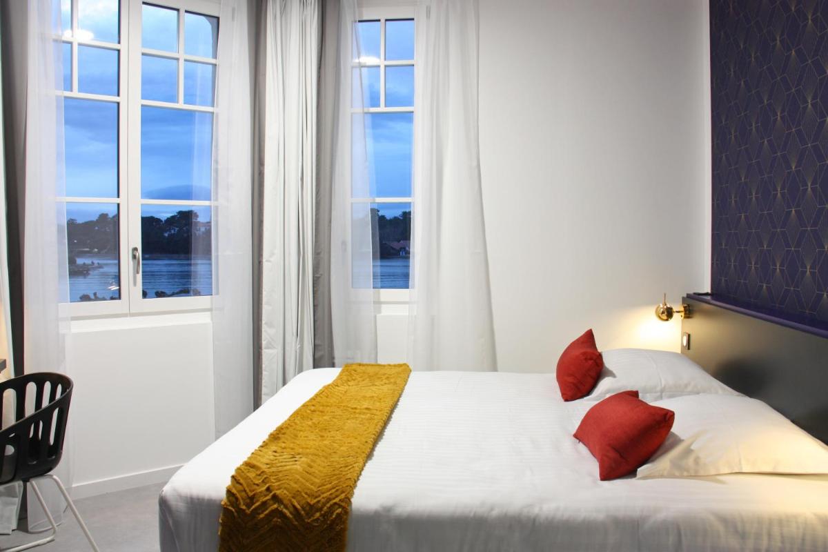 - une chambre avec un lit doté de draps blancs et d'oreillers rouges dans l'établissement Hôtel du Parc & Spa, à Hossegor