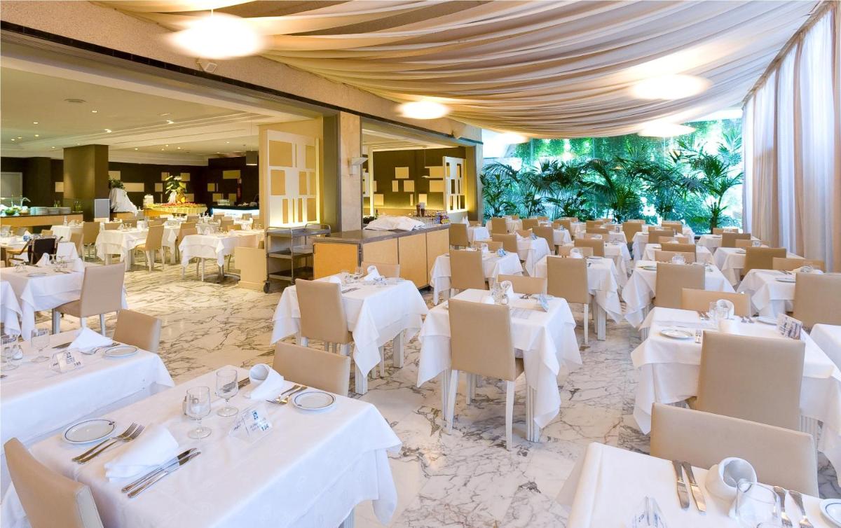 Un comedor con mesas y sillas blancas. en Gloria Palace San Agustín Thalasso & Hotel, en San Agustín