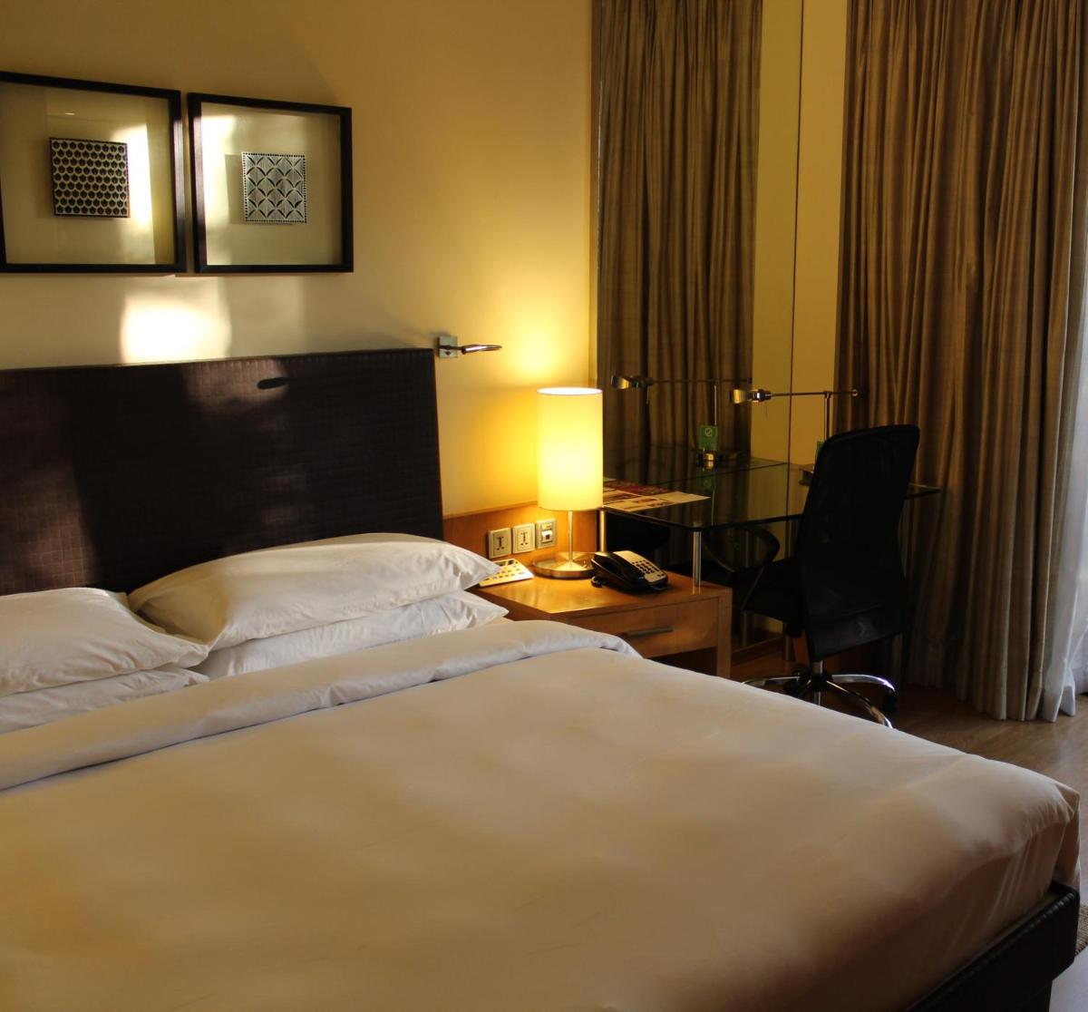 a hotel room with a large bed and a desk at Hyatt Hyderabad Gachibowli in Hyderabad