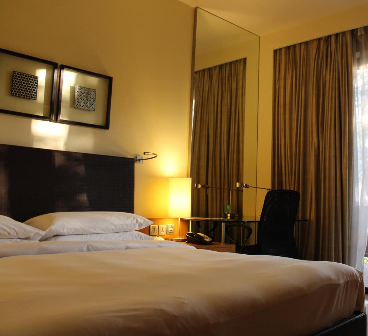 a hotel room with a bed and a mirror at Hyatt Hyderabad Gachibowli in Hyderabad
