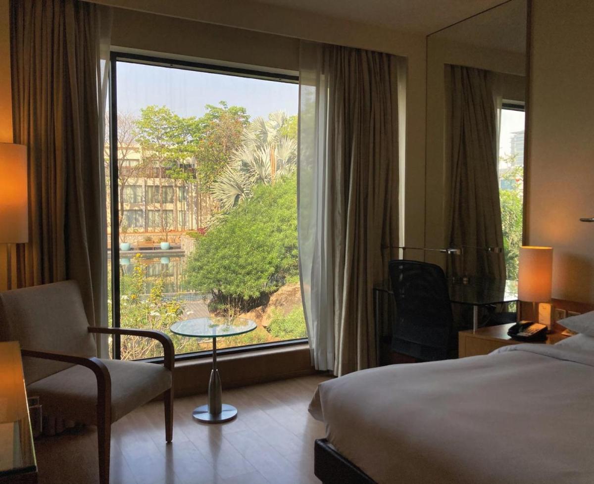 a hotel room with a bed and a large window at Hyatt Hyderabad Gachibowli in Hyderabad