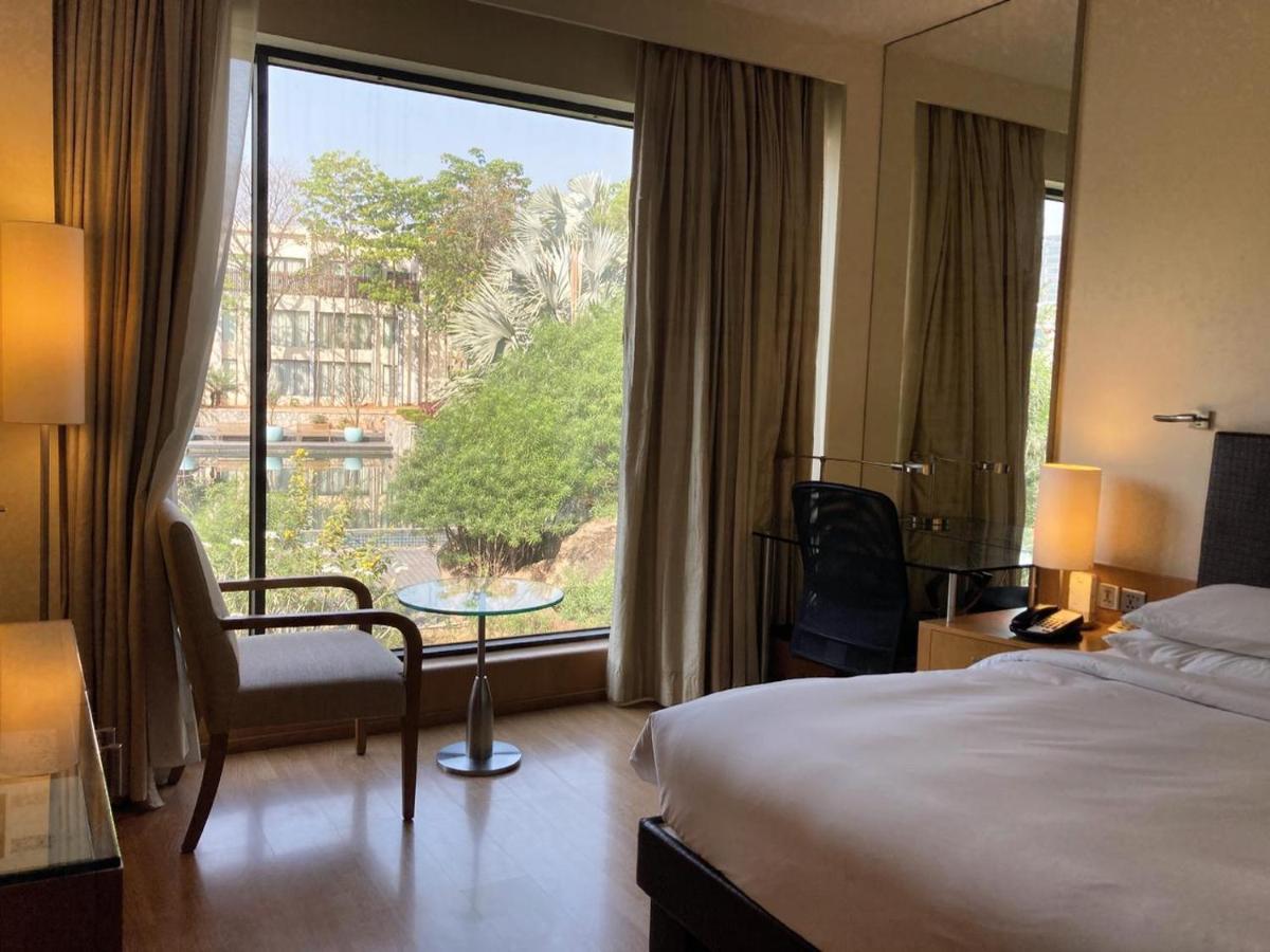 a hotel room with a bed and a large window at Hyatt Hyderabad Gachibowli in Hyderabad