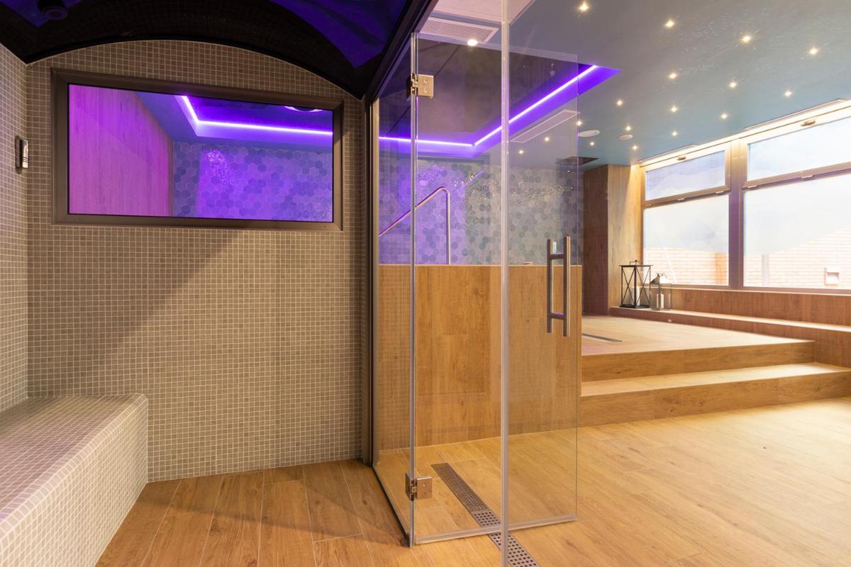 baño con ducha de cristal con luces moradas en Aparthotel Los Girasoles, en Zaragoza