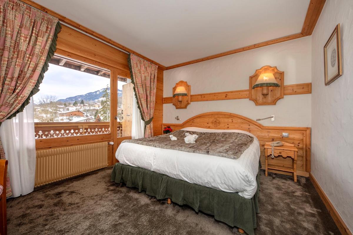 une chambre avec un lit et une grande fenêtre dans l'établissement Chalet-Hôtel Neige et Roc, The Originals Relais, à Samoëns