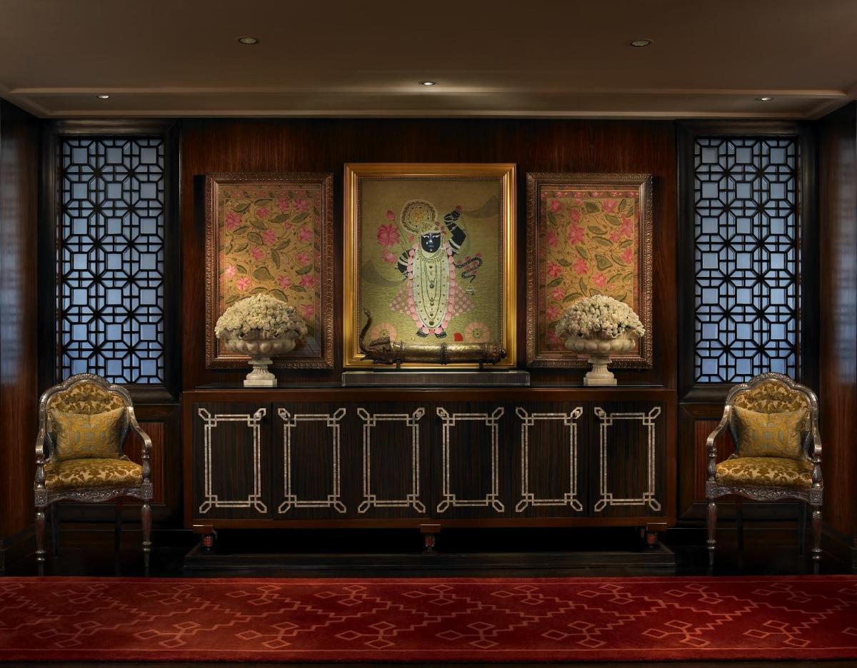 a room with three chairs and paintings on a wall at The Leela Palace Udaipur in Udaipur