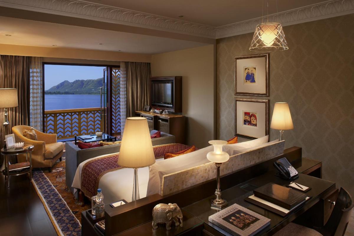 a hotel room with a bed and a living room at The Leela Palace Udaipur in Udaipur