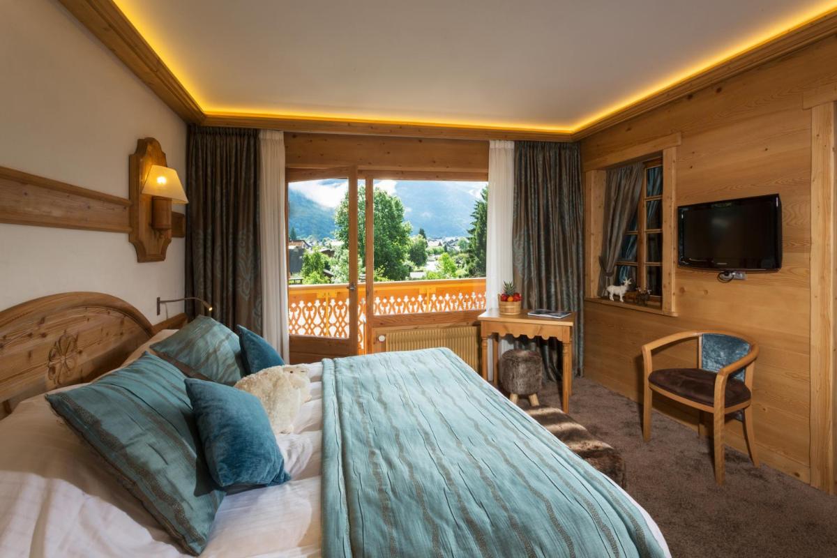 une chambre avec un lit, une télévision et une fenêtre dans l'établissement Chalet-Hôtel Neige et Roc, The Originals Relais, à Samoëns