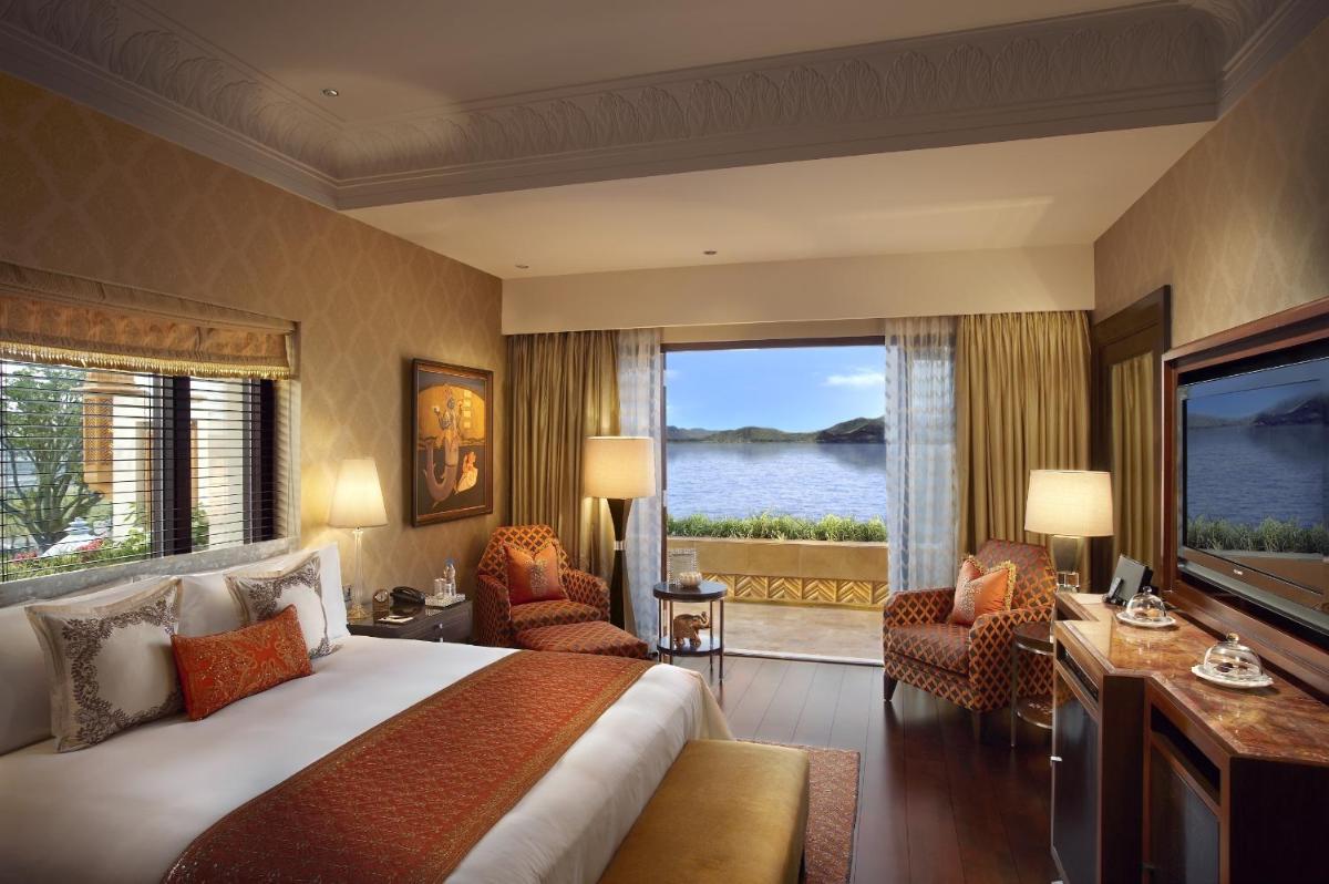 a bedroom with a large bed and a large window at The Leela Palace Udaipur in Udaipur