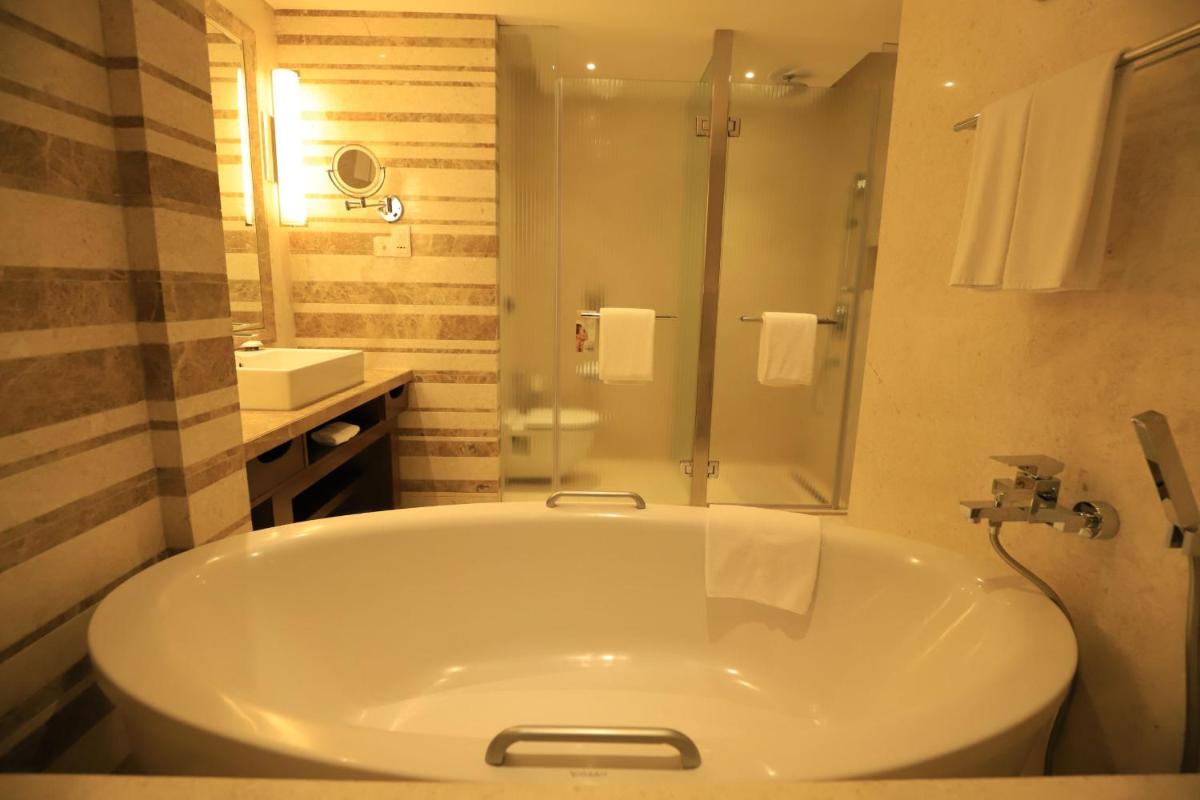 a bathroom with a tub and a shower and a sink at Crowne Plaza New Delhi Okhla by IHG in New Delhi