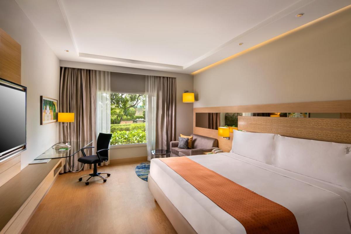 a hotel room with a large bed and a desk at Holiday Inn Agra MG Road an IHG Hotel in Agra