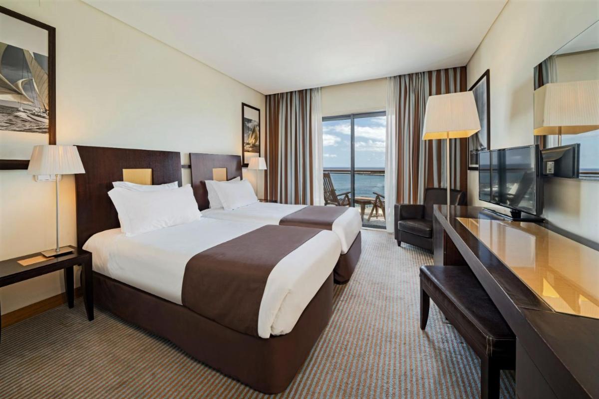 um quarto de hotel com uma cama grande e uma televisão em Hotel Marina Atlântico em Ponta Delgada