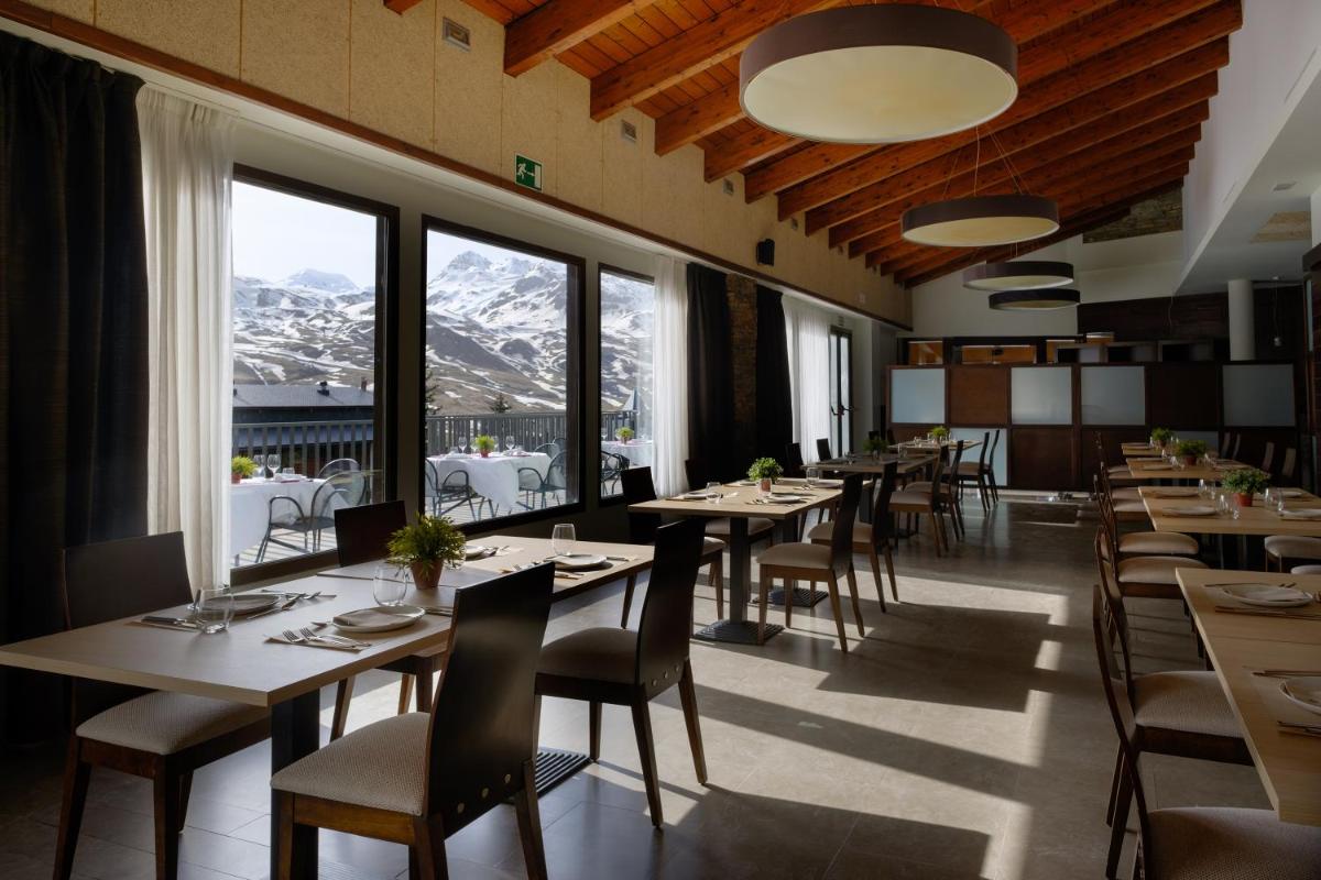 un restaurante con mesas, sillas y montañas en Snö Aragon Hills, en Formigal