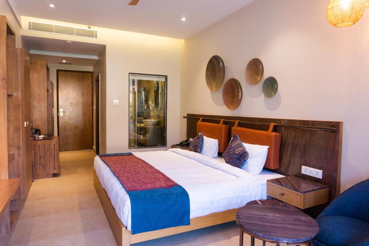a bedroom with a large bed and a blue couch at Antalya By Divine Ganga Cottage in Rishīkesh