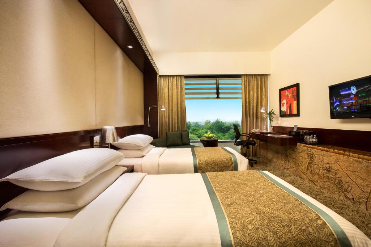 a hotel room with three beds and a television at Crowne Plaza Ahmedabad City Centre by IHG in Ahmedabad