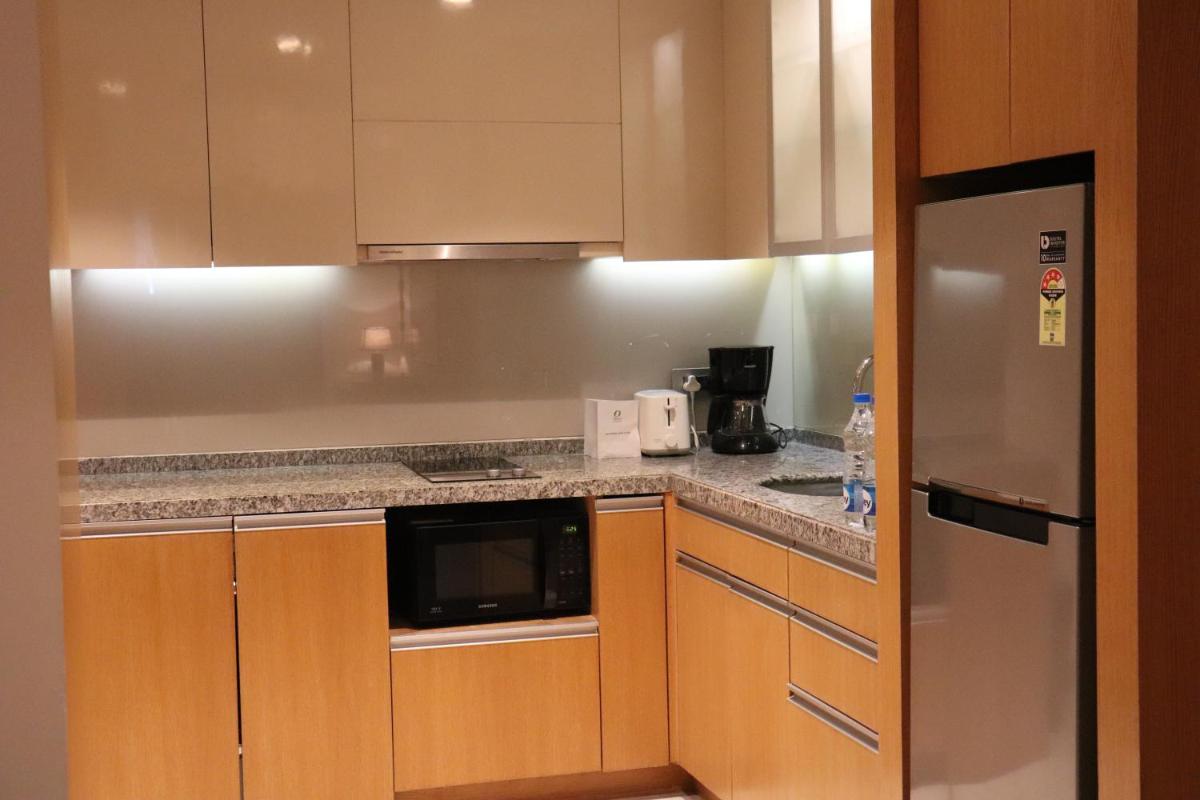 a kitchen with wooden cabinets and a stainless steel refrigerator at Oakwood Residence Kapil Hyderabad in Hyderabad