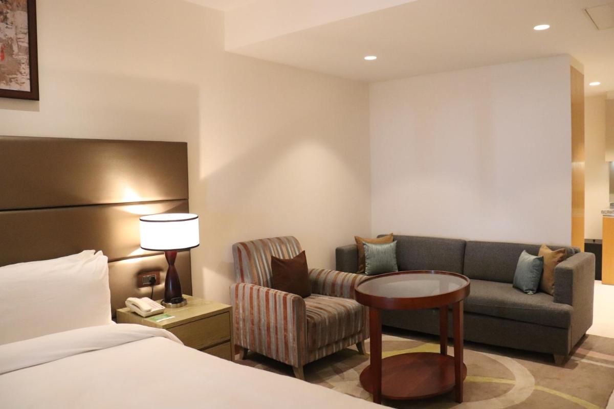 a hotel room with a bed and a couch and a chair at Oakwood Residence Kapil Hyderabad in Hyderabad