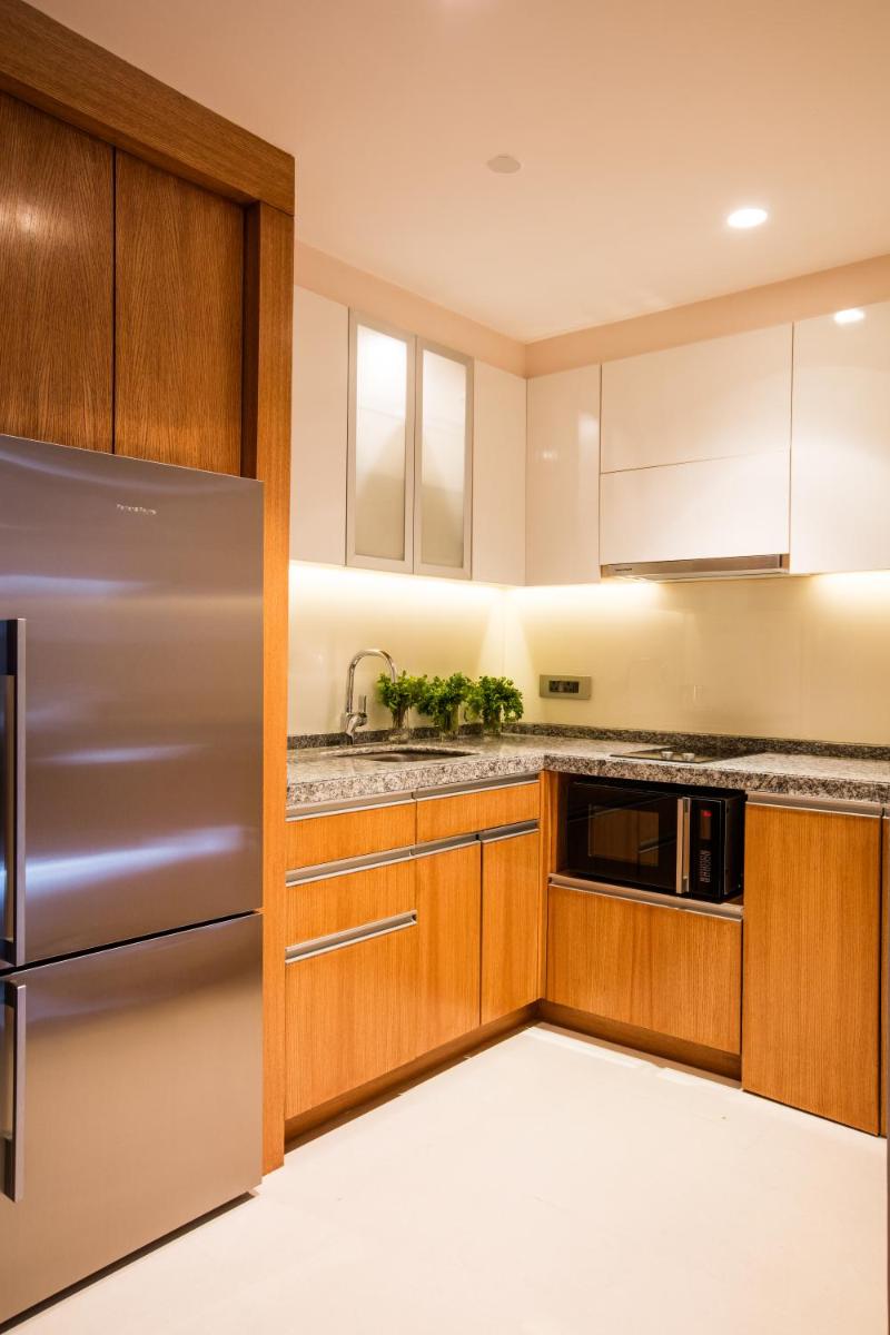 a kitchen with wooden cabinets and a stainless steel refrigerator at Oakwood Residence Kapil Hyderabad in Hyderabad