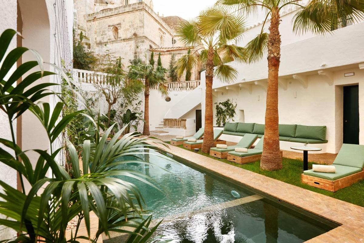 un patio con piscina y palmeras en Faustino Gran Relais & Chateaux, en Ciutadella
