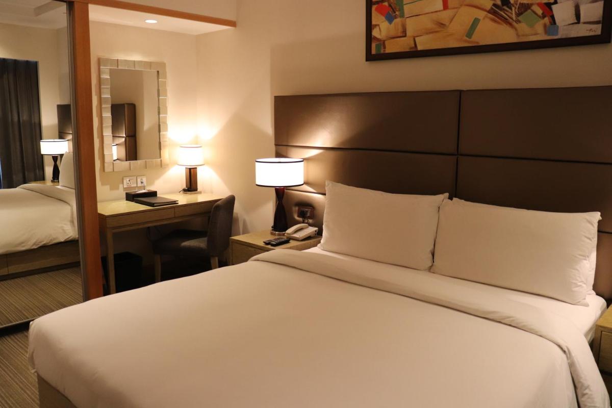 a hotel room with a large bed and a mirror at Oakwood Residence Kapil Hyderabad in Hyderabad
