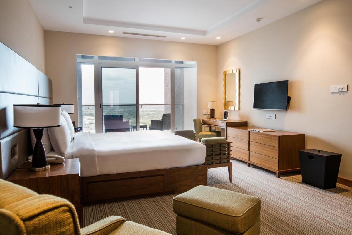 a hotel room with a bed and a desk and a television at Oakwood Residence Kapil Hyderabad in Hyderabad