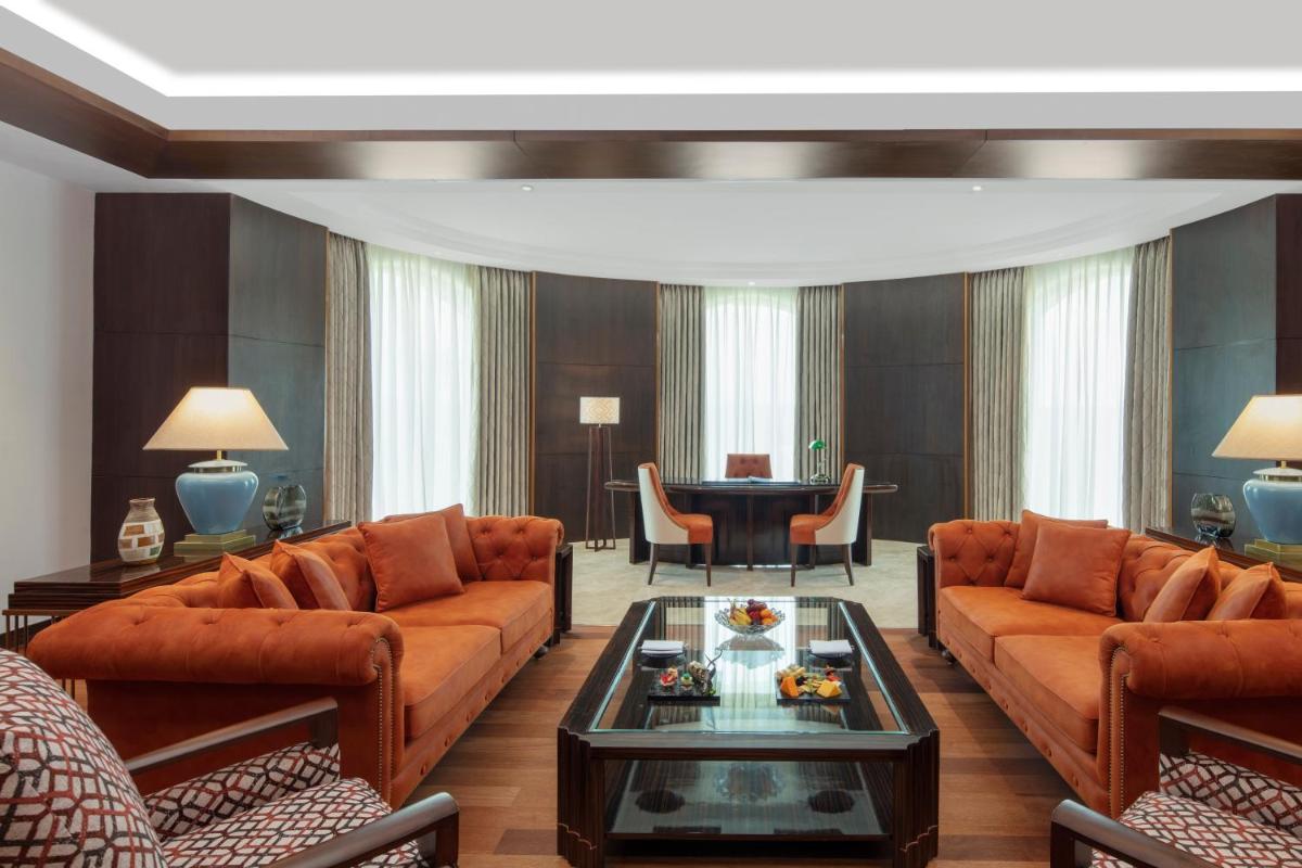 a living room with orange couches and a table at Radisson Blu Plaza Hotel Mysore in Mysore