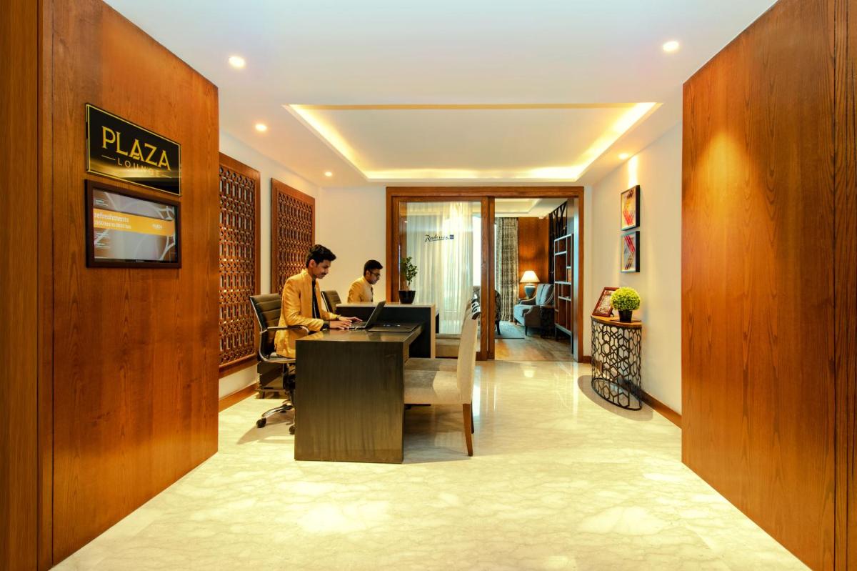 two people sitting at a table in a hotel lobby at Radisson Blu Plaza Hotel Mysore in Mysore