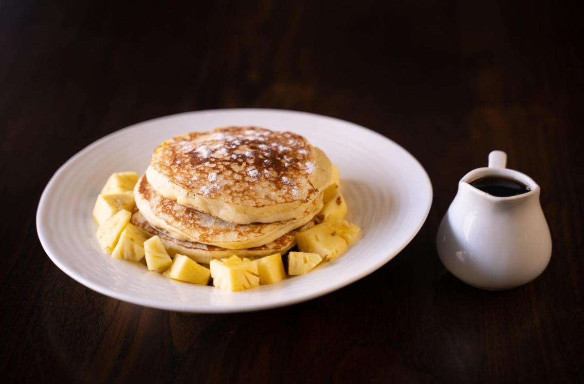 a plate with a stack of pancakes and a cup of coffee at Antalya By Divine Ganga Cottage in Rishīkesh