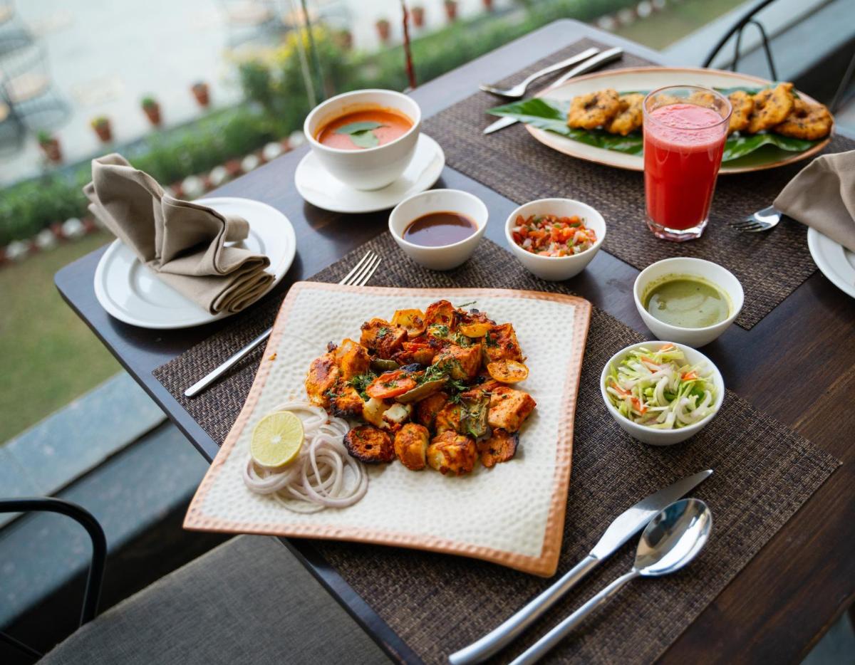 a table with plates of food and drinks on it at Antalya By Divine Ganga Cottage in Rishīkesh