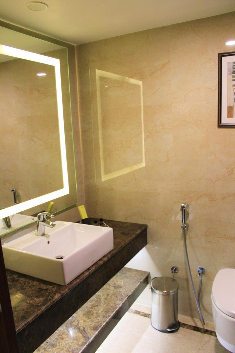 a bathroom with a sink and a toilet and a mirror at The Accord Metropolitan in Chennai