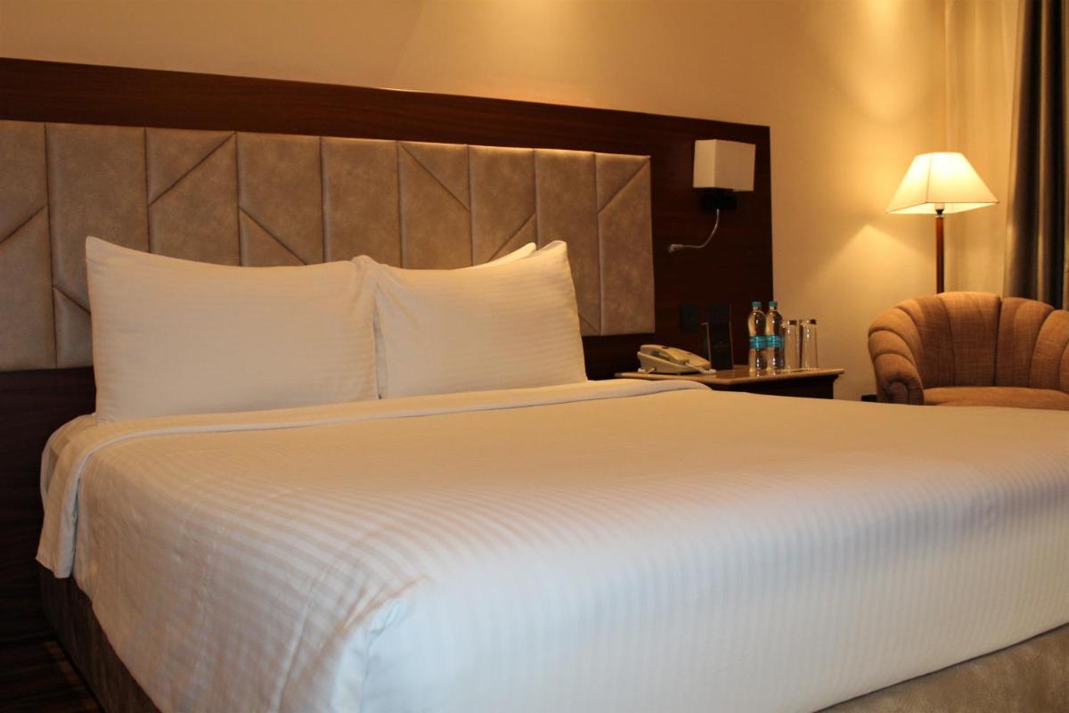 a hotel room with a large white bed and a chair at The Accord Metropolitan in Chennai