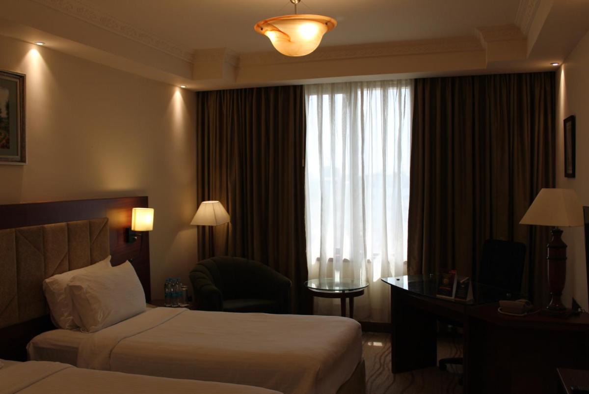 a hotel room with two beds and a desk and a window at The Accord Metropolitan in Chennai
