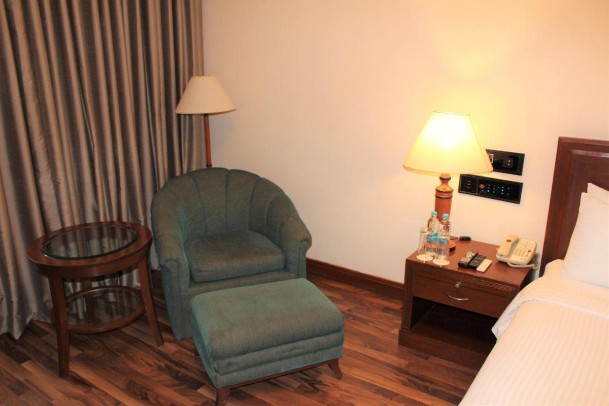 a room with a chair and a lamp and a bed at The Accord Metropolitan in Chennai