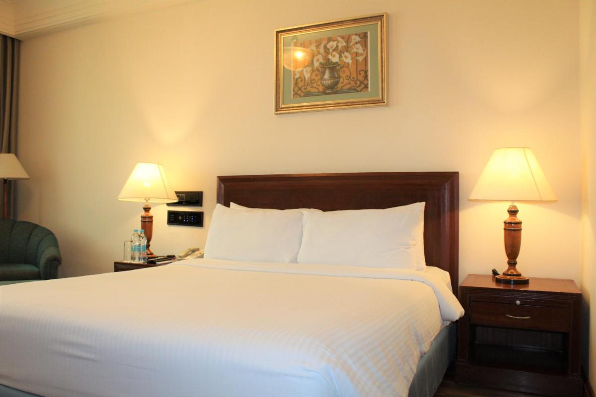 a bed in a hotel room with two lamps on tables at The Accord Metropolitan in Chennai
