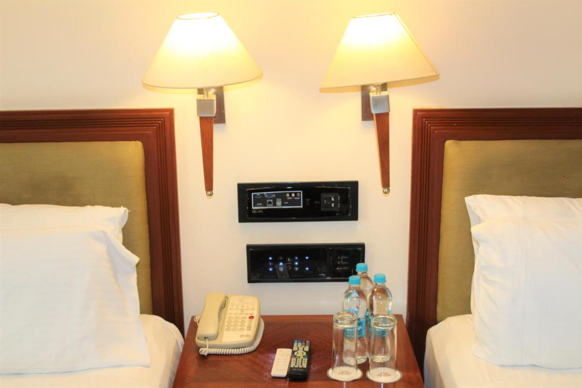 a hotel room with two beds and a phone and two lamps at The Accord Metropolitan in Chennai