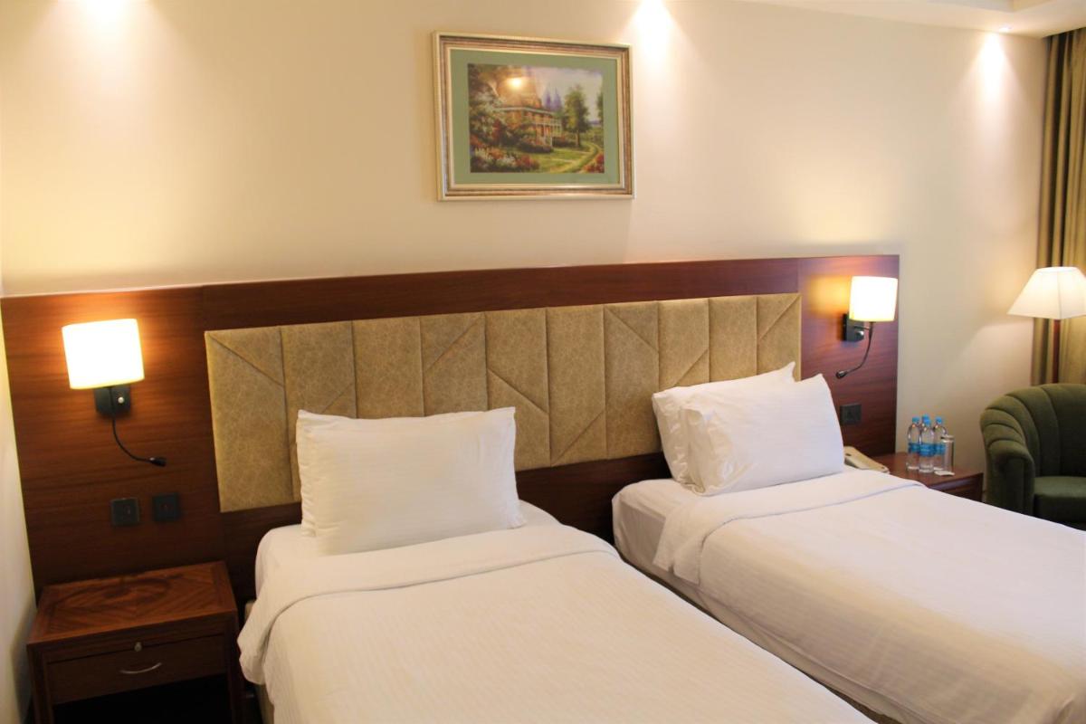 two beds in a hotel room with white sheets at The Accord Metropolitan in Chennai