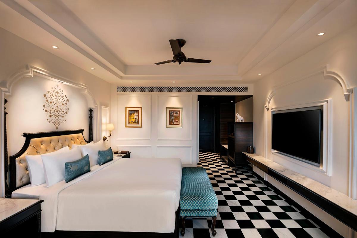 a bedroom with a white bed and a flat screen tv at Aurika, Udaipur - Luxury by Lemon Tree Hotels in Udaipur