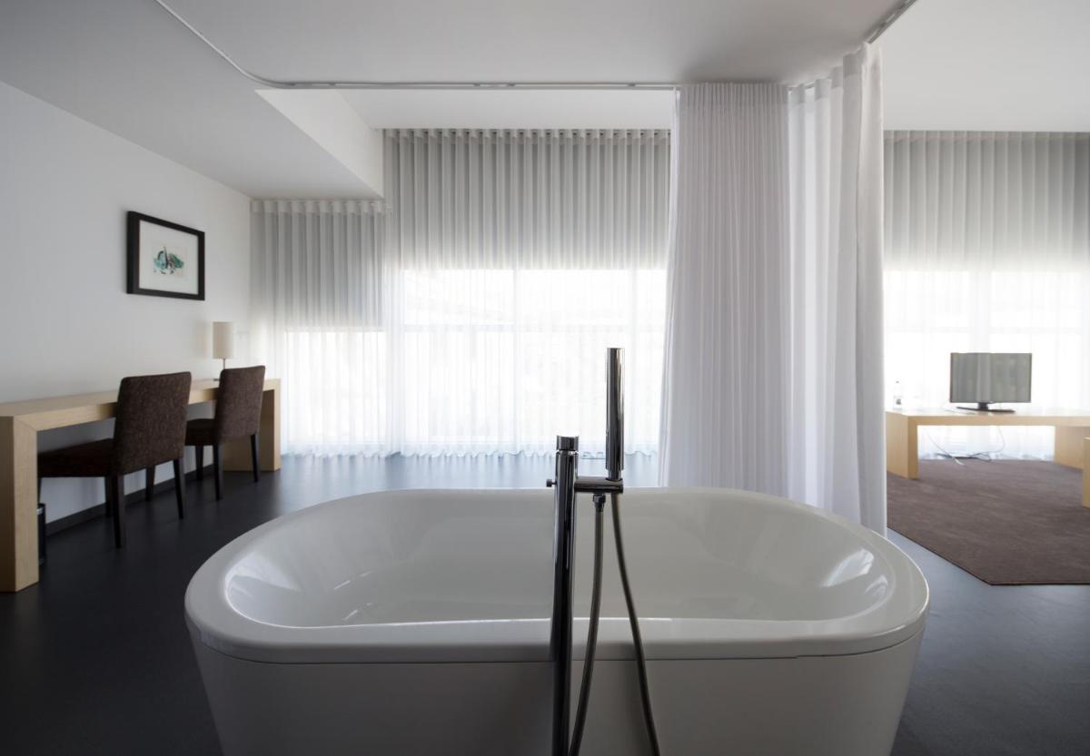 uma banheira branca num quarto com uma mesa em Boticas Hotel Art & SPA em Boticas