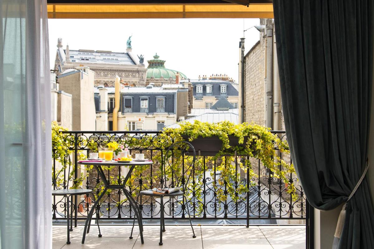 un balcon avec une table et des chaises sur un balcon dans l'établissement Hôtel Saint-Pétersbourg Opéra & Spa, à Paris