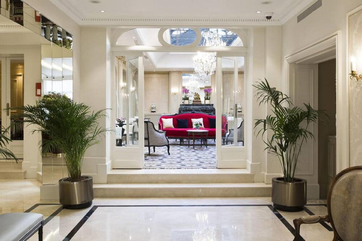 un salon avec un canapé rouge et des plantes dans l'établissement Hôtel Saint-Pétersbourg Opéra & Spa, à Paris