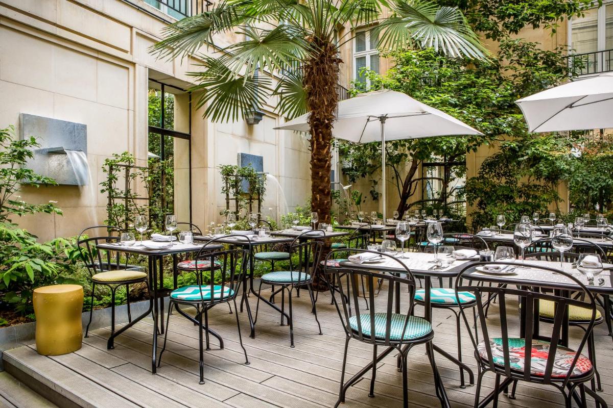 d'une terrasse avec des tables, des chaises et des palmiers. dans l'établissement Sofitel Paris Le Faubourg, à Paris