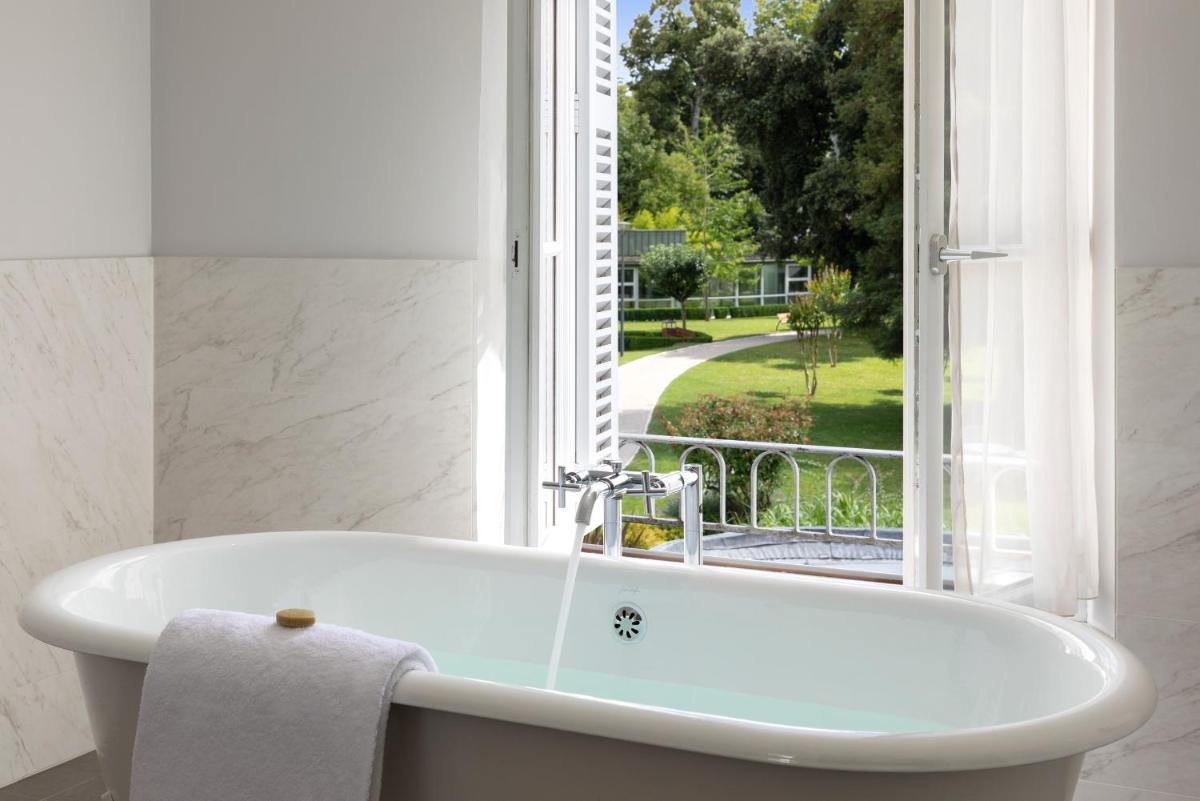 une baignoire dans une salle de bain avec une fenêtre dans l'établissement Château Belmont Tours by The Crest Collection, à Tours