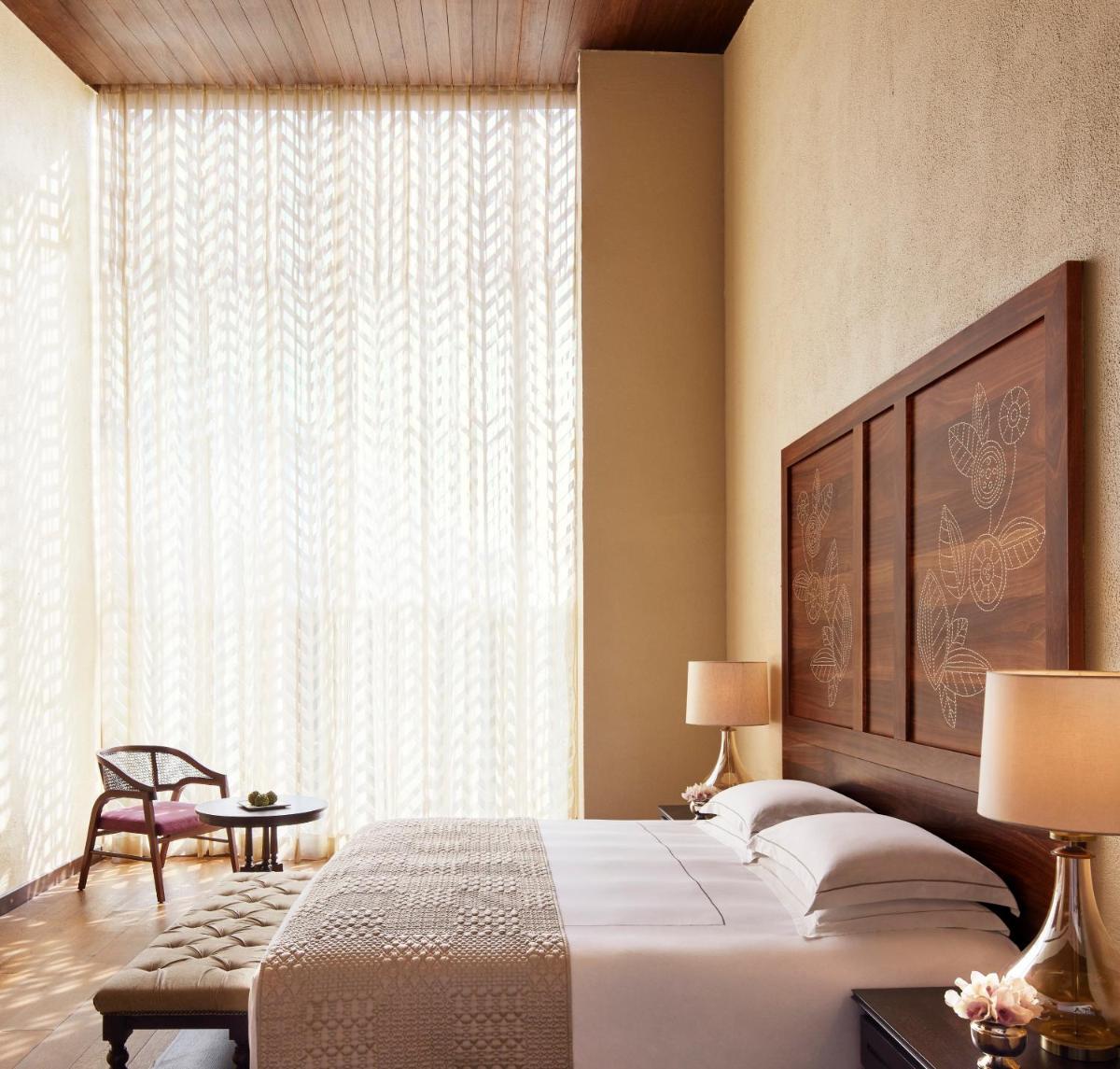 a bedroom with a bed and a large window at Taj Aravali Resort & Spa Udaipur in Udaipur