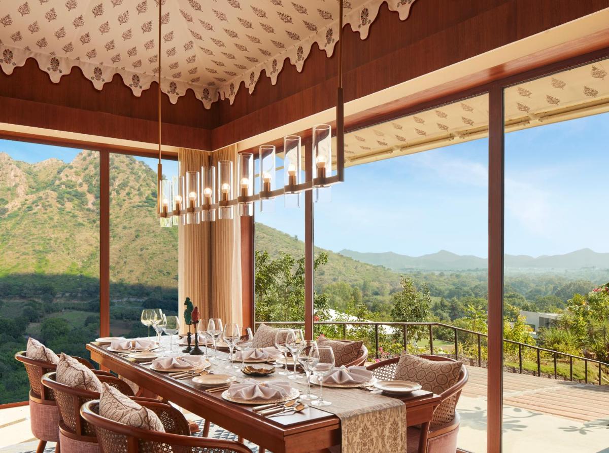 a dining room with a table and chairs and mountains at Taj Aravali Resort & Spa Udaipur in Udaipur