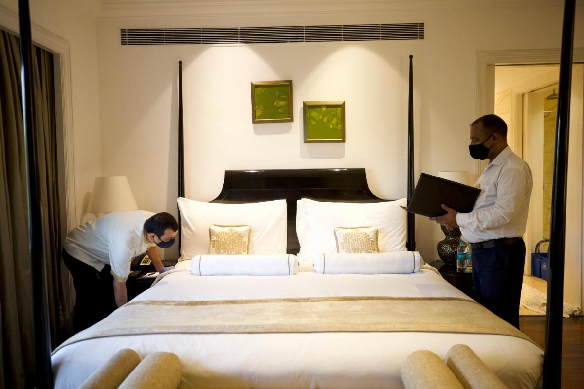 two people standing around a bed in a hotel room at The Claridges New Delhi in New Delhi two people standing around a bed in a hotel room at The Claridges New Delhi in New Delhi