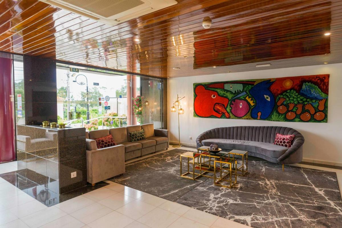 uma sala de estar com um sofá e uma pintura na parede em D. Afonso Hotel & SPA em Monte Real