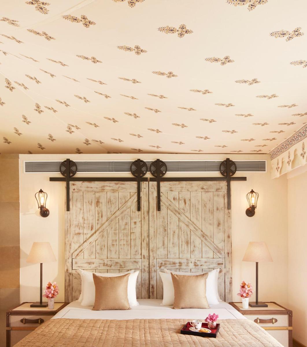 a bedroom with a large bed with a wooden headboard at Taj Aravali Resort & Spa Udaipur in Udaipur