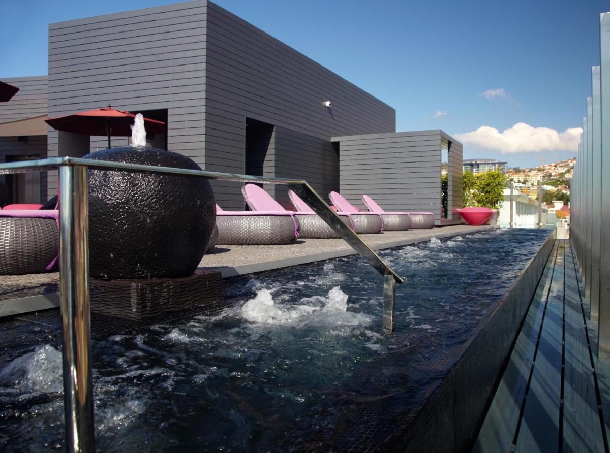 uma piscina com cadeiras cor-de-rosa no topo de um edifício em The Vine Hotel no Funchal