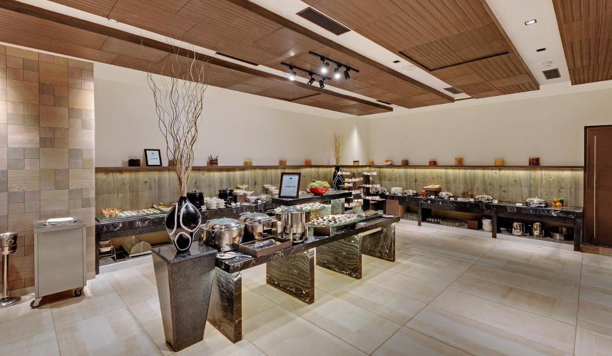 a restaurant with a buffet line in a large room at Wyndham Ahmedabad Shela in Ahmedabad