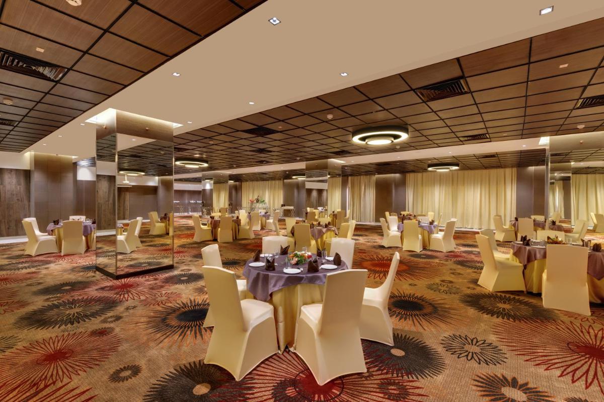 a banquet hall with tables and chairs in a room at Wyndham Ahmedabad Shela in Ahmedabad
