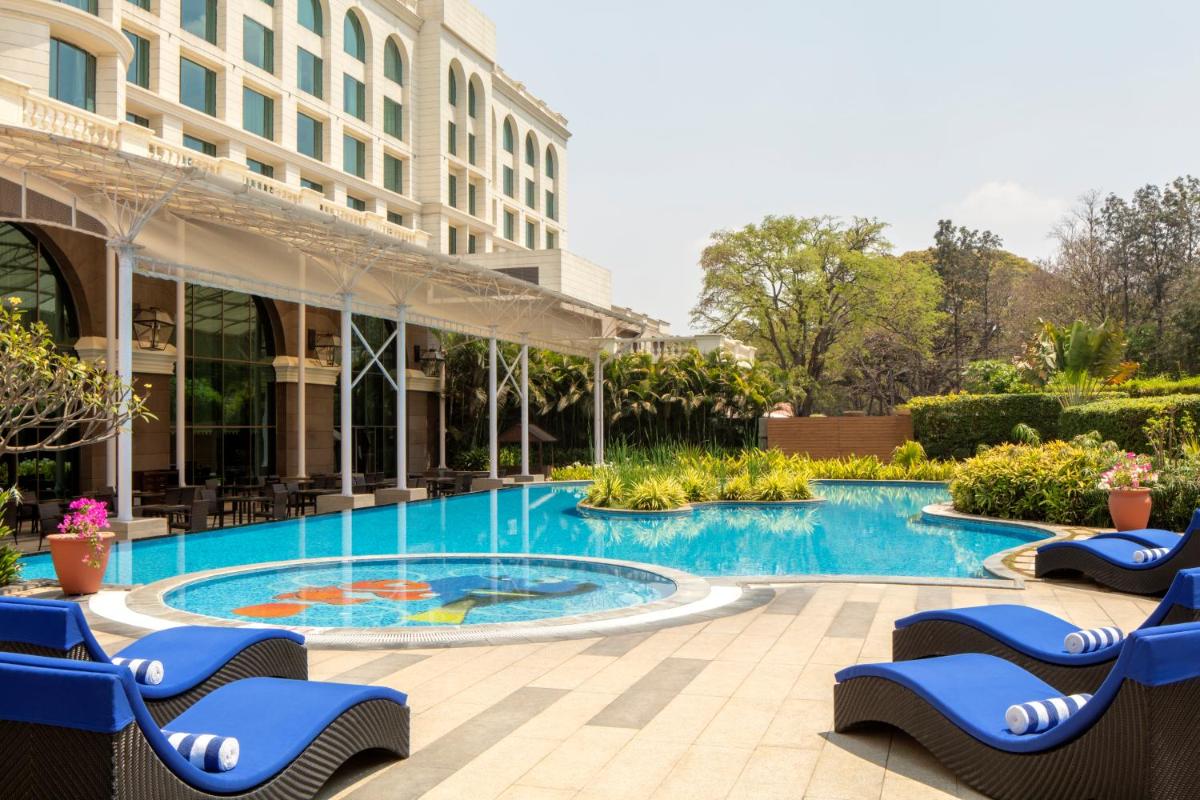a swimming pool with blue chairs and a building at Radisson Blu Plaza Hotel Mysore in Mysore